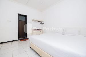 - une chambre avec un grand lit blanc dans l'établissement Dukuh Kupang Residence Mitra RedDoorz, à Surabaya