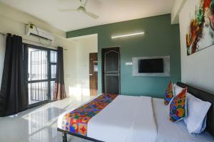 a bedroom with a bed and a tv on the wall at FabHotel Elite Homes in Nagpur
