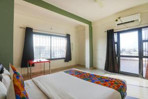 a bedroom with a bed and a desk and two windows at FabHotel Elite Homes in Nagpur
