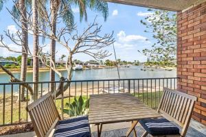 a wooden table and two chairs on a balcony with a river at Anjuna, 2 bedroom apartment on canal in Mooloolaba +2 photos