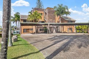a brick house with palm trees in front of it at Anjuna, 2 bedroom apartment on canal in Mooloolaba