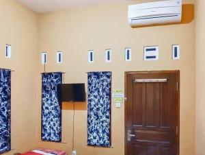 a room with blue and white curtains and a door at RedDoorz at Rita Guesthouse Pangandaran in Pangandaran