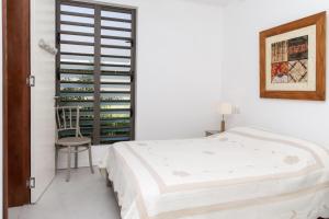 - une chambre blanche avec un lit et une chaise dans l'établissement Beach Villa Mauritius, à Roches Noires