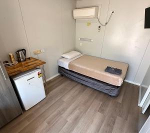 a small room with a bed and a small refrigerator at Roebuck Plains Roadhouse in Broome