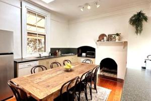 a kitchen with a wooden table and a fireplace at Carinya Cottage in Myrtleford