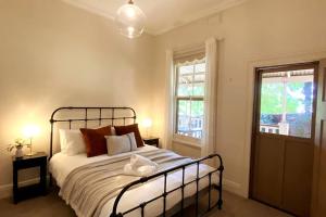 a bedroom with a large bed with two windows at Carinya Cottage in Myrtleford