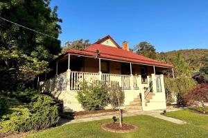 a house with a red roof and a yard at Carinya Cottage in Myrtleford
