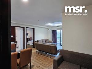 Kota Kinabalu City Ensuite by MSR at SCSP Ming Garden في كوتا كينابالو: غرفة معيشة مع أريكة وغرفة مع سرير