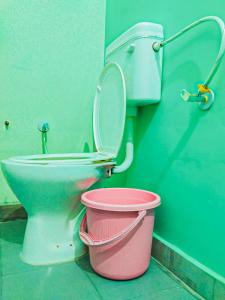 a bathroom with a toilet and a pink bucket at m.i. guest house in Bikaner