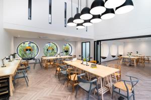 Un comedor con mesas y sillas y ventanas. en Blu Monkey Hub and Hotel Krabi Town, en Krabi