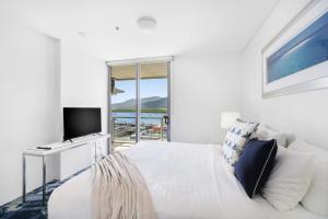a white bedroom with a bed and a television at Belle Escapes 24 Harbour Lights Water View Apartment in Cairns +27 photos