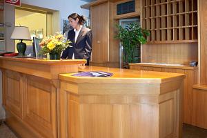 a woman is standing behind a counter with flowers at Albergo Milano in Bossico