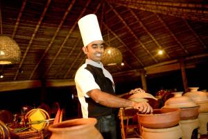 un hombre con un sombrero de chef parado junto a la cerámica en Palagama Beach Resort, en Kalpitiya