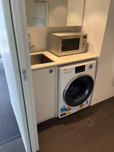 a kitchen with a microwave and a washing machine at Luxurious Apartments Near City in Adelaide