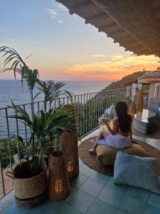 une femme assise sur un balcon pour lire un livre dans l'établissement Vista mozzafiato a picco sul mare Villa Patty, à Torre delle Stelle