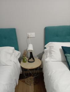two beds next to each other with a lamp on a table at Ecorooms PADRÓN in Padrón
