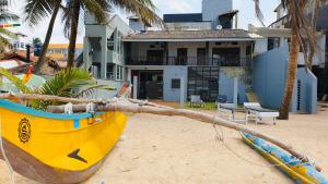 a yellow boat sitting on the beach next to a house at Hikka Beach Flat in Hikkaduwa