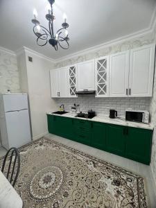 une cuisine verte avec des placards blancs et un lustre dans l'établissement Красивая квартира в центре городе Шымкент. ЖК Аль-Фараби, à Chimkent