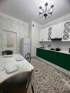 une cuisine avec des placards verts et une table avec des chaises dans l'établissement Красивая квартира в центре городе Шымкент. ЖК Аль-Фараби, à Chimkent