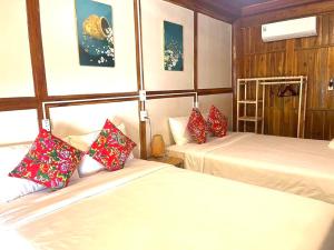 una camera d'albergo con due letti con cuscini rossi di Woodstock Beach Camp a Cat Ba