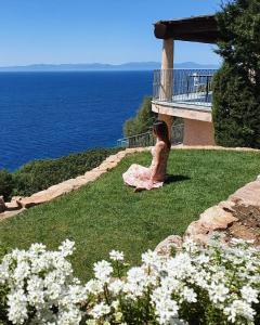 Una donna seduta sull'erba vicino all'oceano di Vista mozzafiato a picco sul mare Villa Patty a Torre delle Stelle