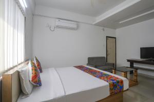 a white bedroom with a bed and a chair at FabHotel Vinayak Inn in Nagpur
