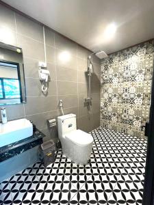 a bathroom with a toilet and a black and white tiled floor at Woodstock Beach Camp in Cat Ba