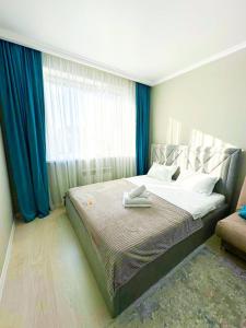 um quarto com uma cama grande e cortinas azuis em New 1 bedroom рядом ханшатыр em Astana