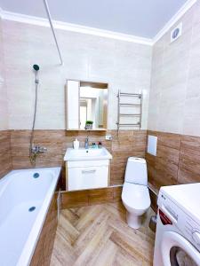 uma casa de banho com uma banheira, um WC e um lavatório. em New 1 bedroom рядом ханшатыр em Astana