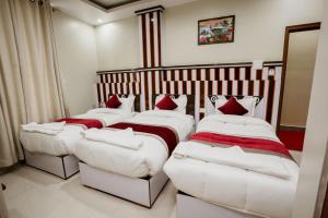 a room with three beds and a bench in it at Hotel Janmabhumi in Pashupatināth