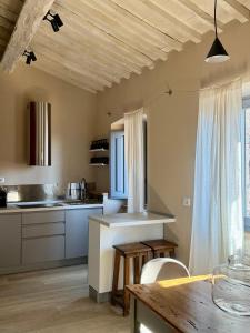 cocina con armarios blancos y techo de madera en Casa Monteme, en Montemerano