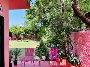 duas cadeiras cor-de-rosa e uma mesa num jardim em Anandmai Heritage Homestay em Jaipur