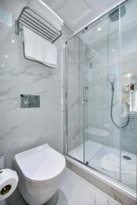 a white bathroom with a shower and a toilet at Queens Park Hotel in London