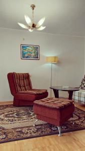 a living room with a couch and a chair and a table at Erdvus butas su balkonu šalia ežero ir stadiono in Visaginas