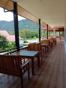 une rangée de tables et de bancs dans une pièce avec des montagnes dans l'établissement Sanhak Guesthouse 1, à Ban Nahin-Nai (2)