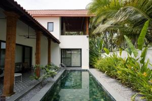 a house with a swimming pool in front of a house at Reunion Ocean Givaah in Udupi