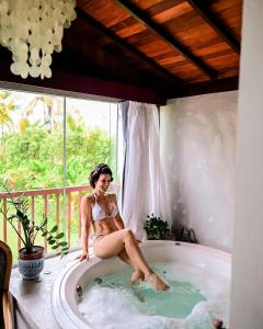 Pousada Villa Tainá Bahia في ارايال دايودا: امرأة جالسة في حوض الاستحمام