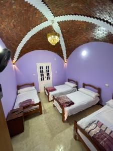 Habitación con 3 camas y techo con lámpara de araña. en Desert Escape siwa -with palm & olive Garden - Hot Spring, en Siwa