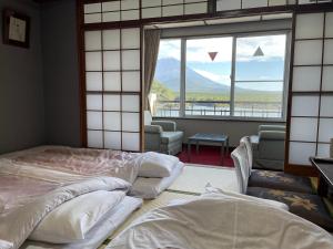 two beds in a room with a large window at Shoji Lake Hotel in Fujikawaguchiko