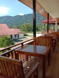 a deck with wooden benches and a table with a view at Sanhak Guesthouse 1 in Ban Nahin-Nai (2)