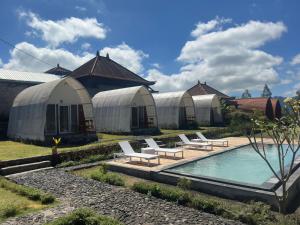 a group of tents with a pool and lounge chairs at Volcano rim Glamping Kintamani in Kubupenlokan