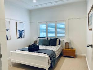 Dormitorio blanco con cama con almohadas azules en Family Getaway to Manly Beach plus free onsite parking, stroll to beach, cafes, en Sídney