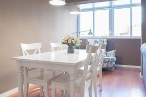 a white dining room table with white chairs and a vase of flowers at At rueda Lopez in Almería