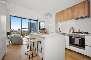 eine Küche mit einer Theke und einigen Hockern in der Unterkunft Modern Elegance 2BR Luxury Apartment with Gym & Pool in Melbourne