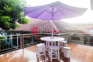 una mesa con una sombrilla púrpura en el balcón en Janna Guest House SYARIAH Yogyakarta Mitra RedDoorz en Yogyakarta