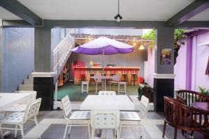 a restaurant with tables and chairs and a purple umbrella at Janna Guest House Syariah Yogyakarta Mitra RedDoorz in Yogyakarta