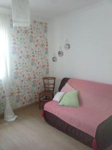 ein Schlafzimmer mit einem rosa Bett und einem Stuhl in der Unterkunft Maison à la campagne idéalement située dans le 63 in Beauregard-lʼÉvêque