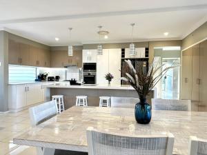 a kitchen with a table with chairs and a vase with flowers at Luxury Holiday Home in Middle Ridge Toowoomba in Harristown