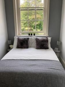 a bed with pillows in a bedroom with a window at Fifty Shades of Gorgeous Greys in London