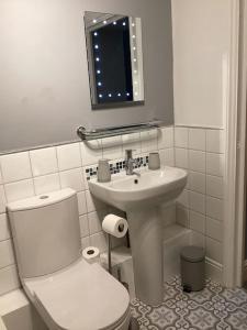 a white bathroom with a toilet and a sink at Fifty Shades of Gorgeous Greys in London
